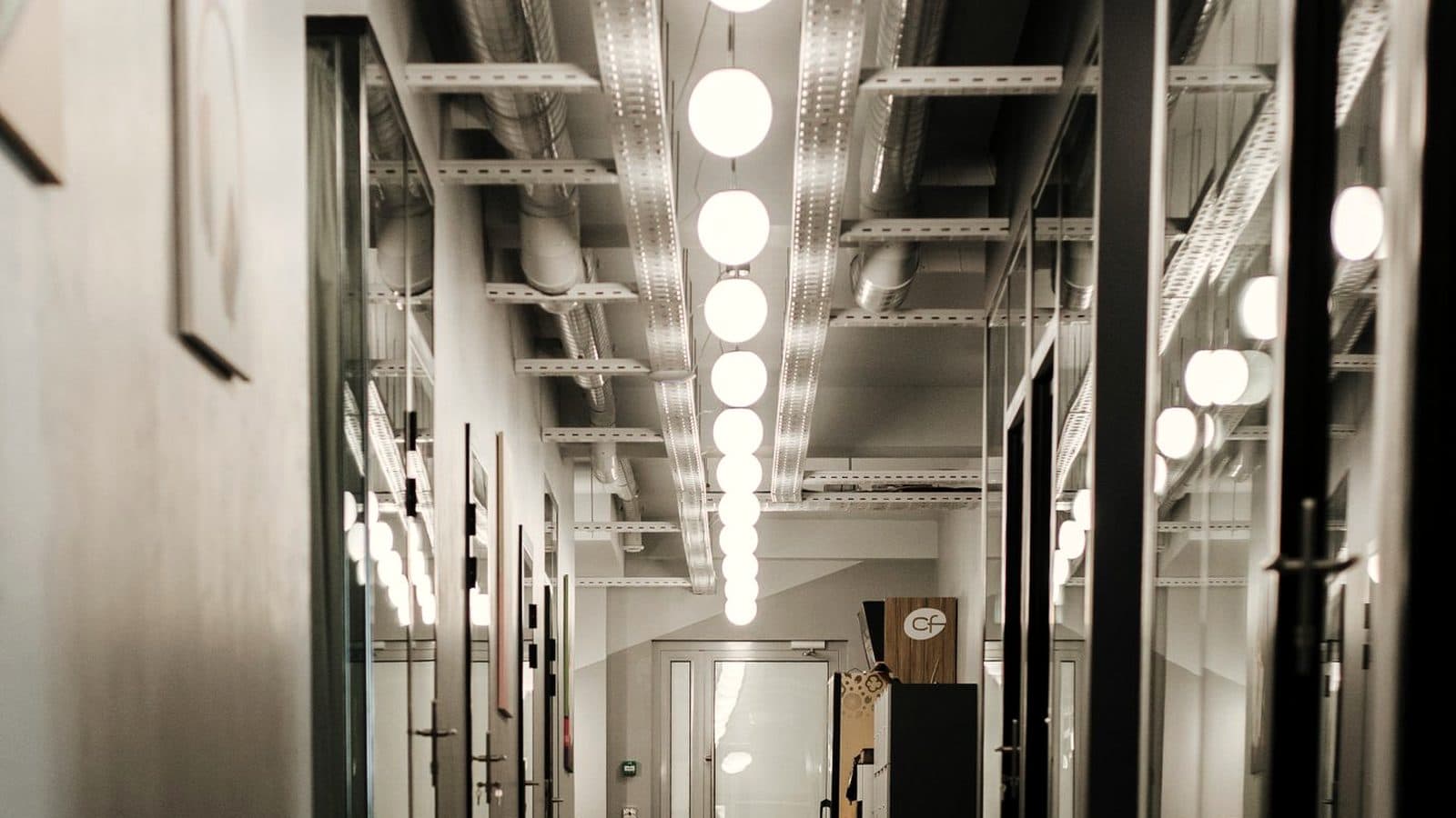 Bürogebäude-Flur mit Glastrennwänden am frühen Morgen, bevor die Mitarbeitenden kommen